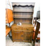 A reproduction oak Welsh style dresser with linen fold panel cupboards under 37 1/2" wide