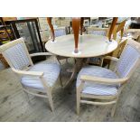 A circular light beech effect single pillar dining table together with four elbow chairs with