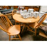 A circular light oak single pillar dining table and four matching stick back Windsor style chairs