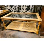 A modern light oak coffee table with inset glass top and cane under tier 45" x 25"