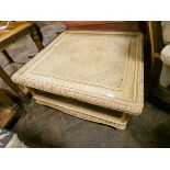 A large square wicker two tier coffee table with glass top