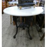 A circular Victorian style iron pub table with cream marble top