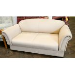 A small two seater settee in cream covering