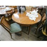 A 1970's G plan circular teak dining room table with fold away centre leaf together with four