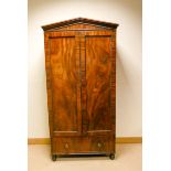 A Regency mahogany two door wardrobe with beaded edged panels with long drawer under fitted brass