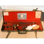 A fitted leather shotgun case with a Holland & Holland label and a few accessory pieces