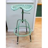 A green adjustable tractor stool