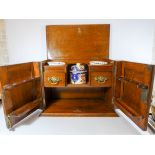 A late Victorian oak smokers cabinet with carved doors, interior drawers and tobacco jar,