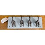 Four iron dogs tail coat hooks on slate base