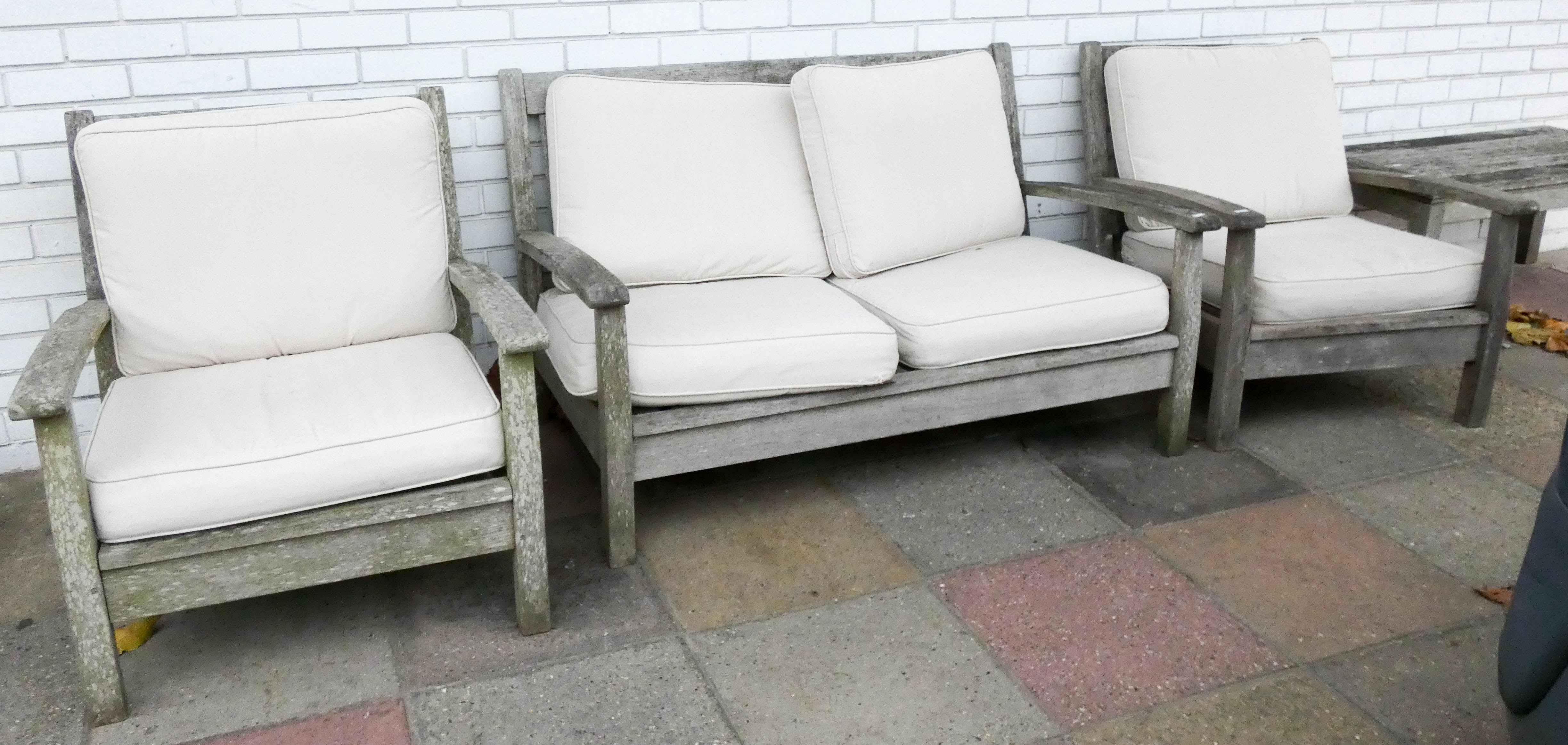 A heavy teak garden bench with faun coloured cushions and two matching chairs with side table