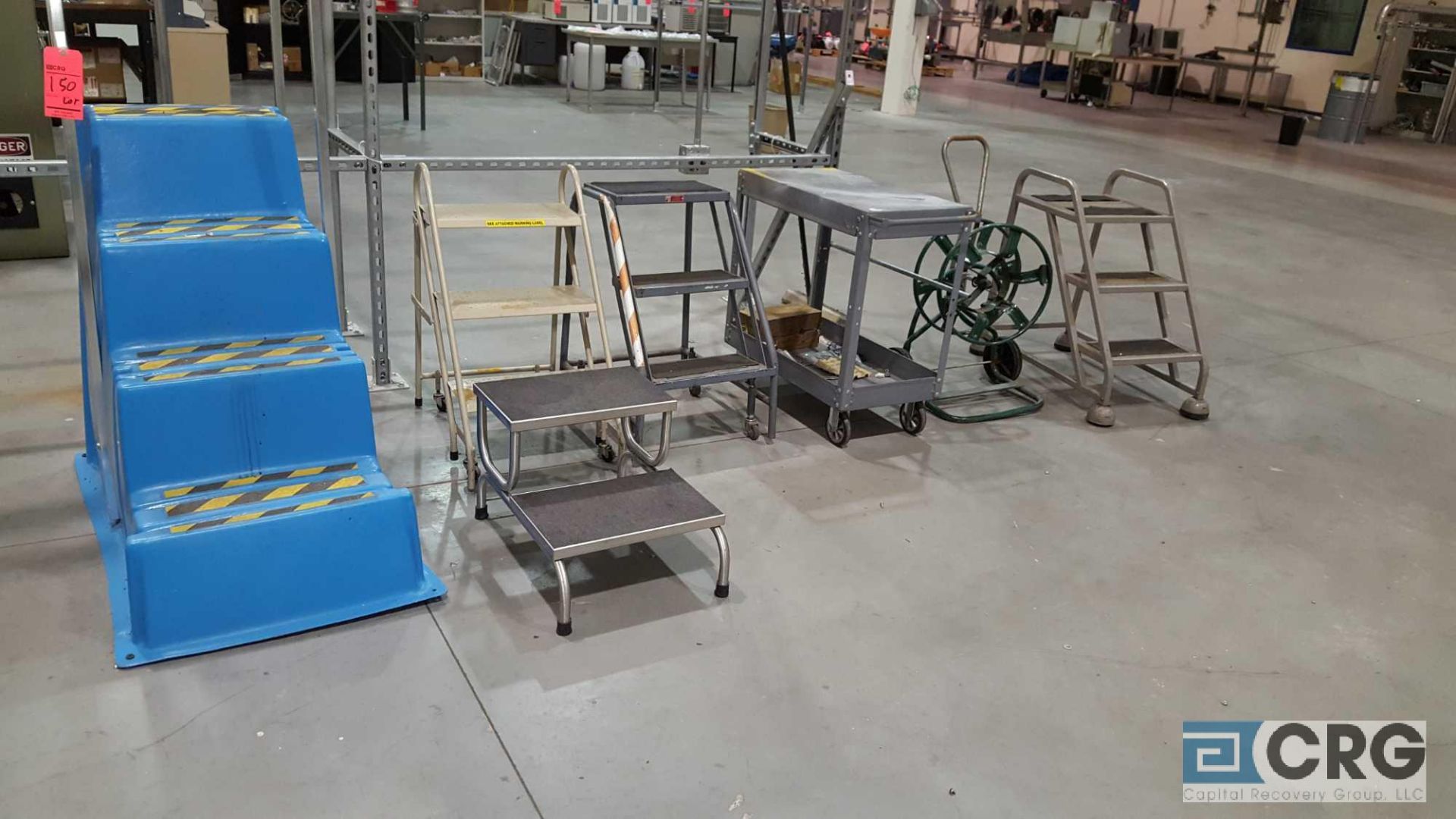 Lot of assorted portable stock ladders, cart, and hose reel.