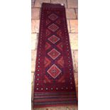 A Persian meshwari runner, with geometric motifs on a red ground,