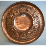 An Arts and Crafts embossed copper circular plaque, decorated fruit and foliage,