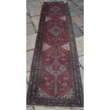 A Persian runner, decorated motifs on a red ground, within a multi border,