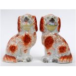 A pair of Victorian Staffordshire pottery figures, of spaniels holding baskets, 18.