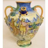 A maiolica drug jar, decorated figures in a landscape, with two spouts and faun mask handles, chips,