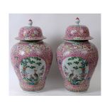 A pair of large Chinese famille rose vases and covers, decorated birds, flowers, and foliage,
