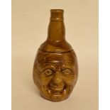 A pottery flagon, decorated face masks, 21 cm high, two other flagons, a porcelain vase,