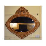 An oval gilt wall mirror, decorated flow