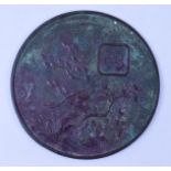 A Japanese bronze mirror, decorated mon,