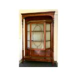 An Edwardian inlaid mahogany display cabinet, with leaf carved and baluster reeded supports,