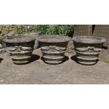 A set of three reconstituted stone garden urns, decorated ribbons and swags,