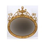 A late Victorian oval gilt gesso wall mirror, surmounted by an urn,