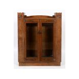 An Art Nouveau oak cabinet, inset with two heart shaped copper panels, decorated tulips,