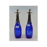 A pair of blue glass decanters, with pla