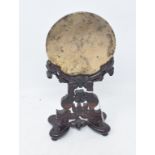 A Chinese bronze mirror, on a carved and