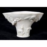 An 18th century Chinese blanc de chine porcelain libation cup, applied animals and scrolling