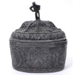 An early 19th century lead oval tobacco box and cover, with figural finial, decorated swags and