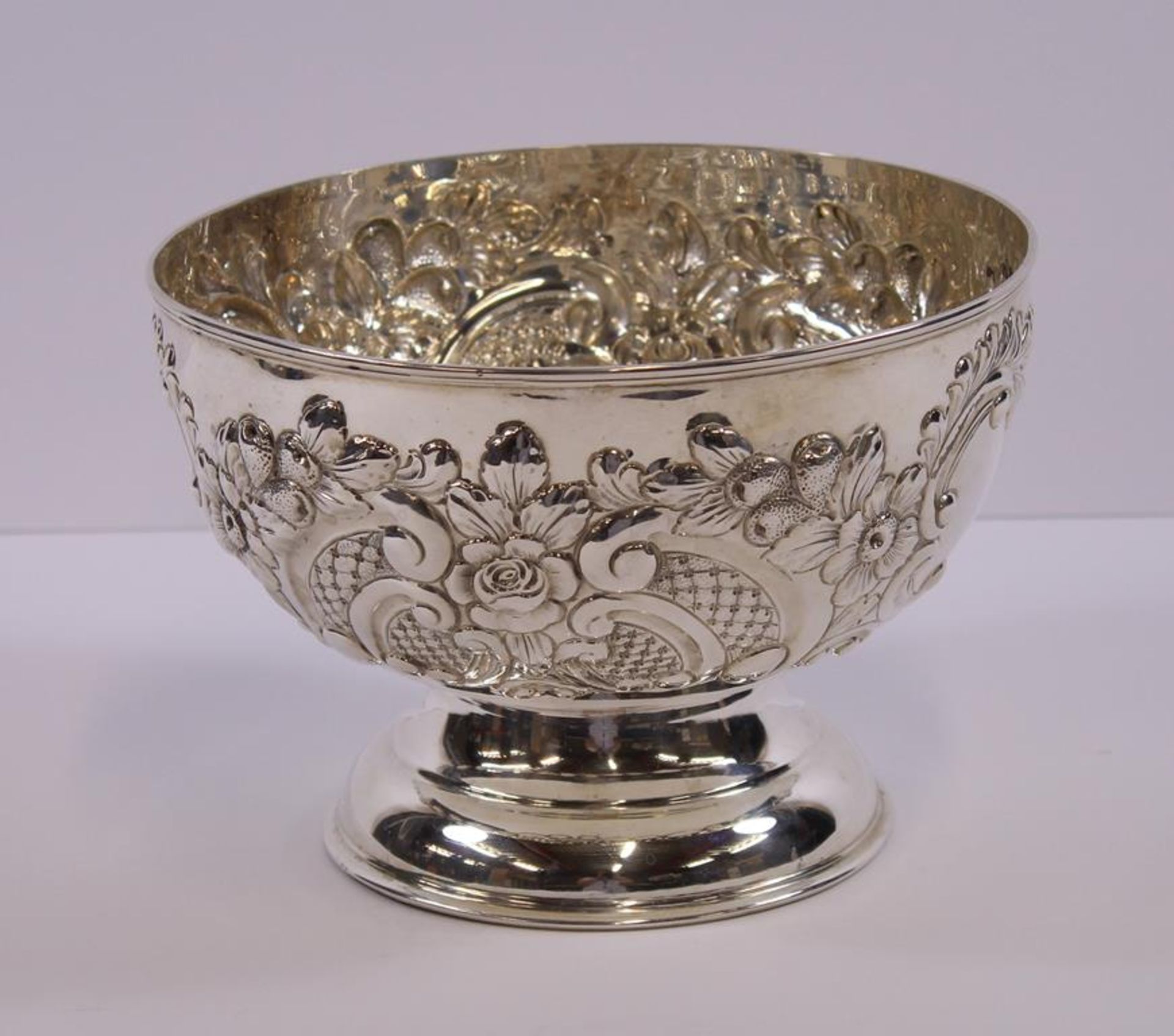 A large silver Rose Bowl of circular form embossed to the sides with flower heads, scrolls and