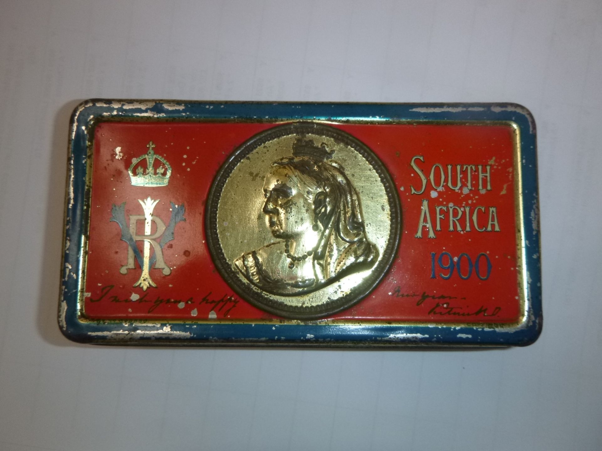 A Queen Victoria Chocolate Tin, South Africa 1900. The lid of the tin is painted red, gold and blue.