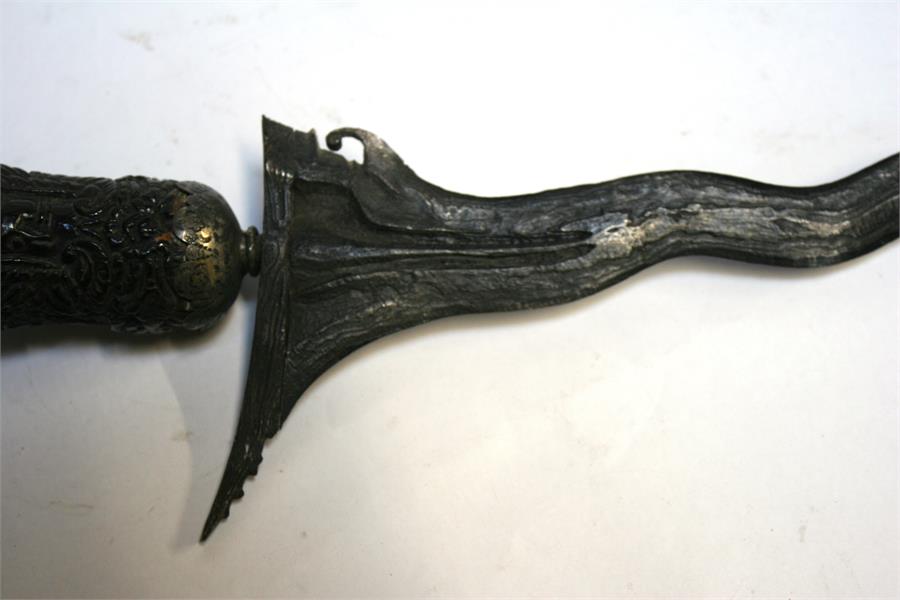 An Indonesian Kris dagger with wavy ornate blade and intricately carved handle, in silver covered - Image 5 of 12