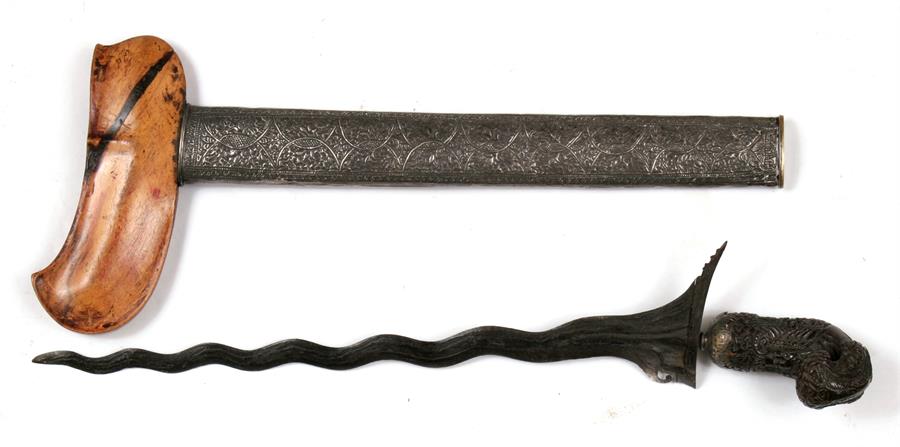 An Indonesian Kris dagger with wavy ornate blade and intricately carved handle, in silver covered