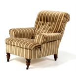 An Edwardian button backed armchair, on turned front supports.