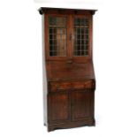 An early 19th century oak bureau bookcase, the pair of leaded glass doors enclosing shelved