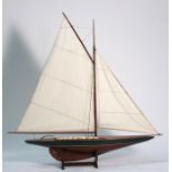 A scratch built mahogany pond yacht on stand, 89cms (35ins) long.
