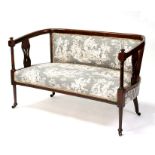 An Edwardian two-seater sofa with upholstered seat and back, with pierced splats, on turned legs,