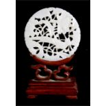 A pierced jade disk, depicting pheasants in foliage, mounted on a hardwood stand, 9cm high