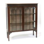 An Edwardian mahogany display cabinet, the pair of glazed doors enclosing a shelved interior, on