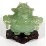 A Chinese jade like two-handled censer with dragon finial and lion mask capped legs, standing on a