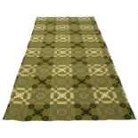 A Welsh handwoven blanket decorated with geometric patterns on a green ground.