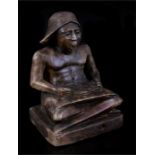 An Egyptian carved stone figure depicting a seated scholar reading a scroll, 25.5cms (10ins) high.