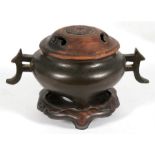 A Chinese bronze two handled censer with silver wire work decoration, standing on three legs, with