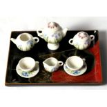 A Japanese porcelain miniature dolls house teaset on lacquer tray, the teapot 3cm (1.1ins) high.