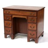A mahogany kneehole desk with single frieze drawer above two pedestals, each with three short
