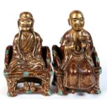 A pair of Chinese ceramic figures in the form of seated scholars with gilt highlights, having an