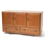 An Ercol sideboard with three cupboards above two long drawers, 129cms (50.75ins) wide.